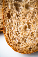 Photo of a fresh homemade delicious brown bread lying on a whit modern flat porcelain plate on a white background