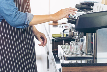 Close up hands coffee barista man make hot cup espresso shot from coffee machine. Cappuccino with milk in italian coffee shop cafe. Close up hands of barista use machine make black drinking hot cup