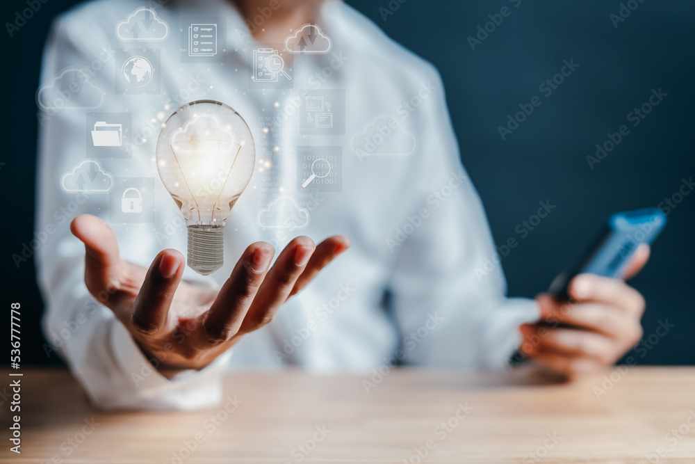 Aufkleber Hand holding virtual lightbulb with cloud computing and technology icon. businessman using smart phone. Cloud management big data include business strategy, backup and upload data in network.