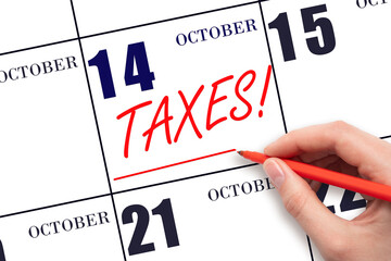 Hand drawing red line and writing the text Taxes on calendar date October 14. Remind date of tax payment