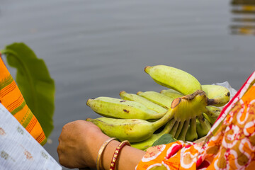 bunchor hand of bananas being held by indian woman in traditional attire of saree and bangles for...