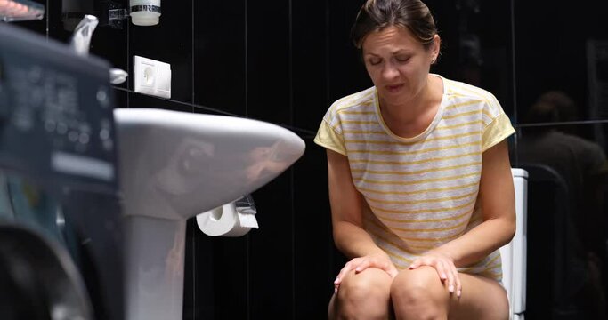 Unhealthy sick woman suffering from diarrhea, constipation and abdominal pain in toilet