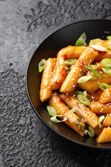 Tteokbokki, Topokki fried rice cake stick in black bowl. Korean street food