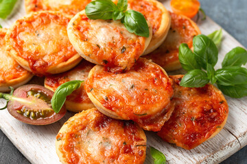 Mini pizzas with tomatoes and mozzarella cheese on white wooden board