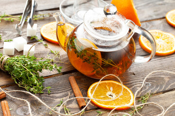 Tea with thyme and orange tea in a transparent teapot