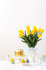 Fototapeta na wymiar Festive interior, yellow tulips in a vase and Easter eggs, cute bunnies and Easter cake