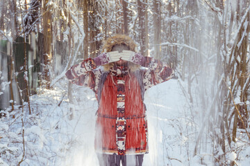 Snow falls on a girl from a tree while walking in a winter forest. High quality photo