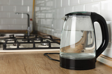 Modern electric transparent kettle on a wooden table in the kitchen.Kettle for boiling water and...