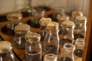 Shallow depth of field (selective focus) details with various glass vials used for old chemical and medical experiments inside a museum.