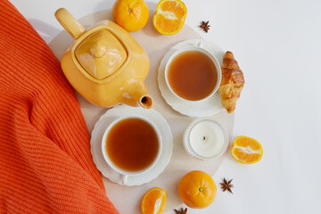 Two cups of tea, teapot, candle, mandarins on the white background.  Home atmosphere. Orange tea...