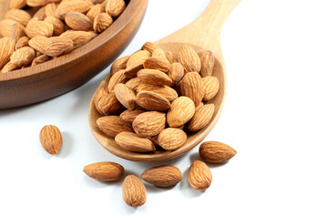 Almonds in a wooden ladle and wooden tray on white background, close up.