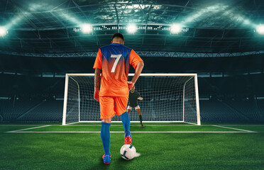 Soccer scene at night match with player in orange uniform kicking the penalty kick