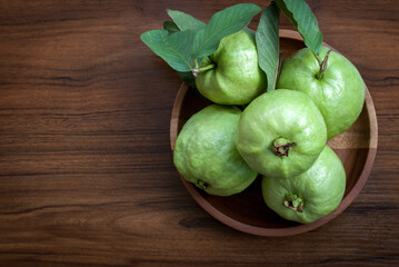 Fresh guava fruit with leaf in a wooden tray on a wooden floor, flat lay, space for text.