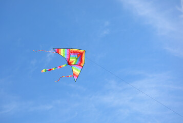 big kite with the colors of the rainbow flying in the blue sky symbol of equality and hope and peace