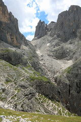 path that descends zigzag on the slope of the Italian alps in summer