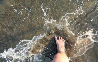 splashes of sea water and the foot of the barefoot person