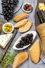 Aperitif set with olives, cheese, baguette and red wine.