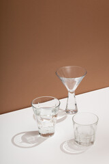 Photo of a modern stylish cocktail, alcohol glasses shot in trendy minimalistic style on a white table with brown background
