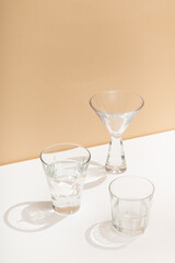 Photo of a modern stylish cocktail, alcohol glasses shot in trendy minimalistic style on a white table with beige background
