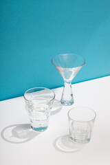 Photo of a modern stylish cocktail, alcohol glasses shot in trendy minimalistic style on a white table with blue background
