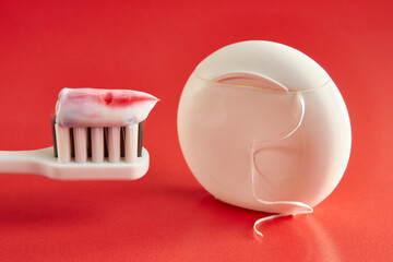 Toothbrush with toothpaste and dental floss on a red background. Dental care. Oral hygiene.