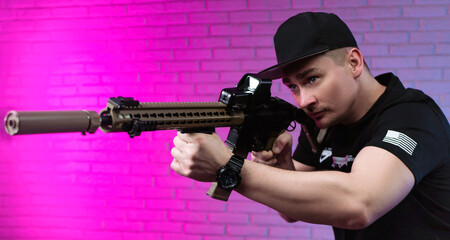 a male special agent with an automatic airsoft rifle on a neon background