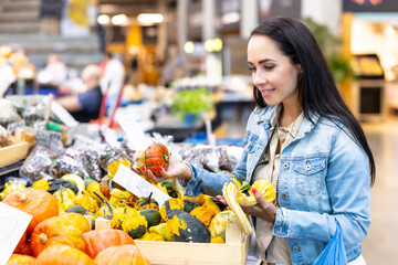 Smiling woman checks on pumpkins offered for sale in the grocery store
