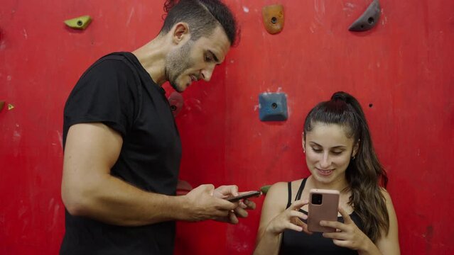 Close up of young woman and his personal trainer conversating at the gym. She is showing him her smartphone 