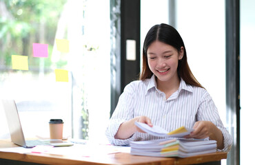 Fototapeta premium Asian business woman working in office with laptop paper work.