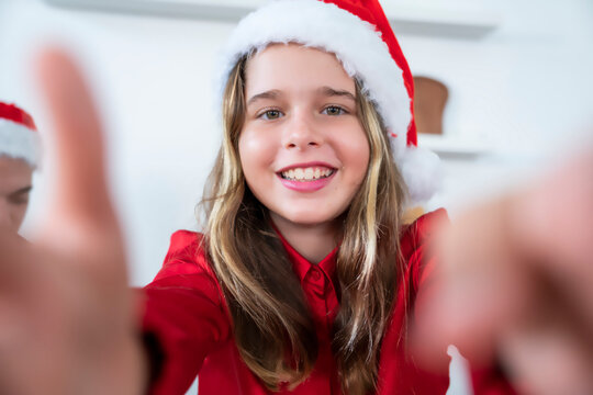 10-year-old girl holds her smartphone camera and takes a selfie in her living room during the New Year and Christmas holidays.