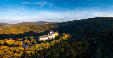 Naklejka premium panorama of Lockenhaus Castle surrounded by autumn forest in warm evening light