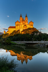 historic Melk Abbey in warm evening light with reflections in the calm Danube River