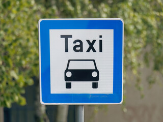 Close-up photo of a blue Taxi stand sign attached to a metal pole