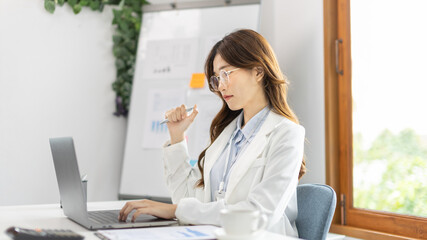 Businesswoman using laptop to work, Asian woman working in the office, Financial clerk or accountant with documents and equipment working on the desk, Using computers for financial transactions.