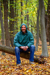 Bearded man with yellow maple leaf in autumn in the forest. Portrait of a man in the autumn forest. The bearded man stands, sits, walks in the autumn forest. The concept of nature, parks, recreation.