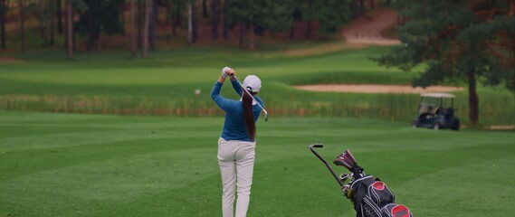 Caucasian female playing golf, striking a ball during the course