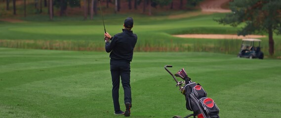 Caucasian man playing golf, striking a ball during the course