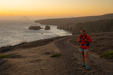 Woman In Orange Coat Stands On Trail Over The Santa Cruz Island Cliffs