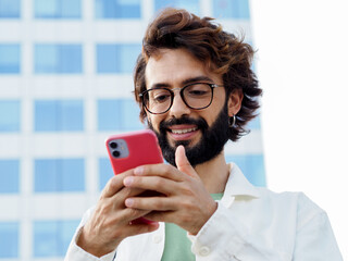 Italian young smiling man chatting with a mobile phone in a city