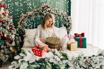 Obraz na płótnie Canvas A woman in pajamas opens Christmas gifts.