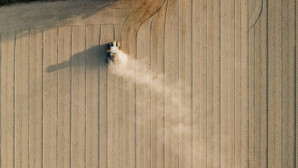 Aerial view of tractor extruding ground to compact soil levelling rural field