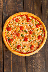 Pizza with tomato and pesto sauce. On a wooden table.