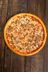 Pizza with cheese and minced meat. On a wooden table.