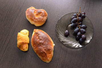 cake, crescent roll and grapes at the brown table