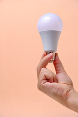 LED eco light bulb in hand on beige background.