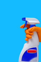 Sprayer for cleaning windows and plumbing in hand with glove on blue background.