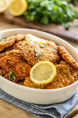 Detail of crispy fresh schnitzels with sesame seeds served with slice of lemon and parsley