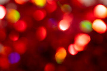 Multicolored bokeh on a red defocused blurred background.