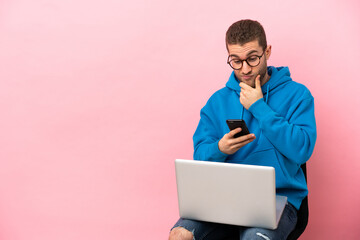 Young man sitting on a chair with laptop thinking and sending a message