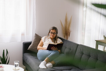 Lifestyle portrait of woman reading a book at home